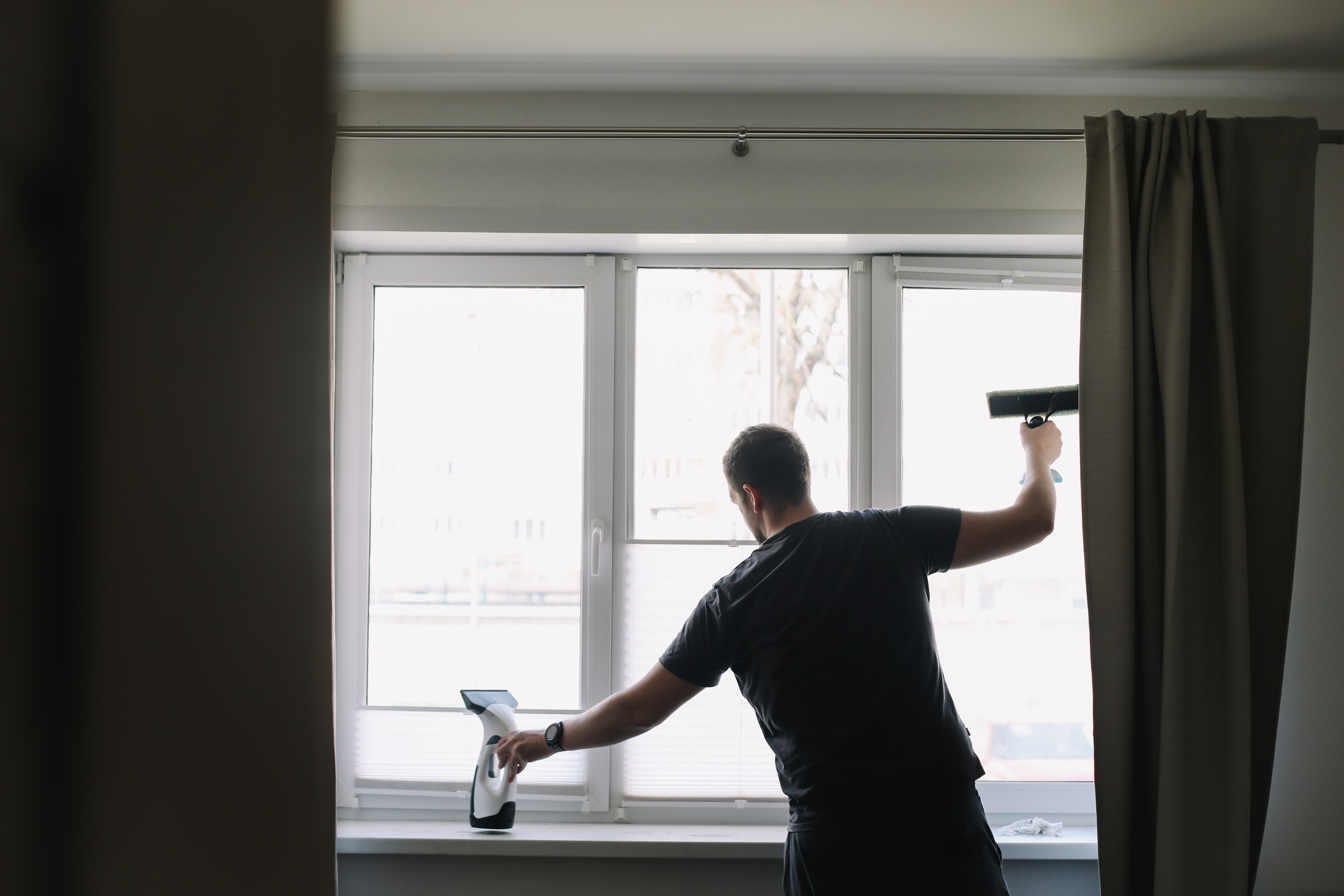 Man washing and cleaning window at home. Housework and housekeeping, home hygiene
