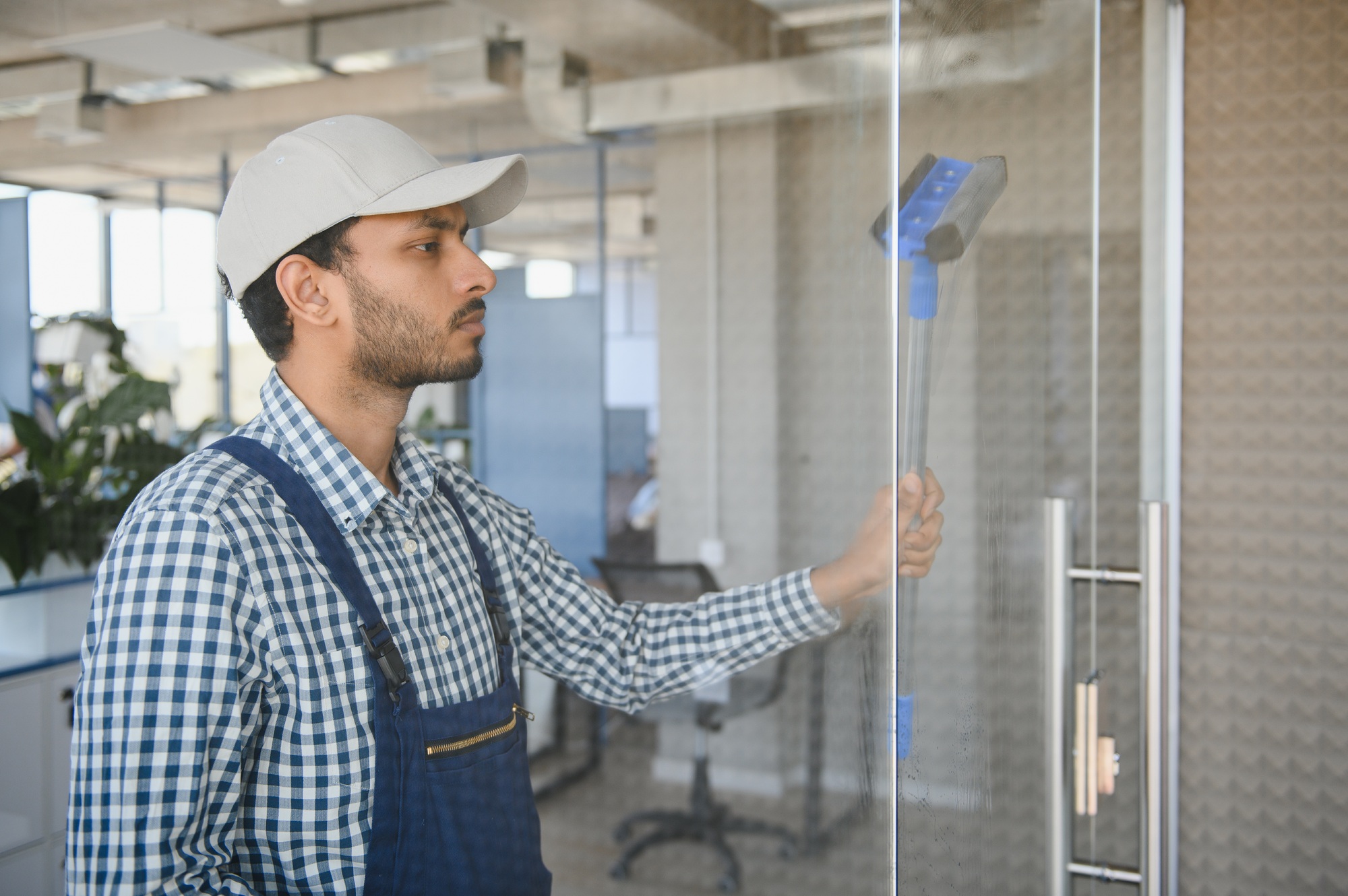 Young indian man washing window in office